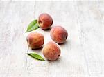 Four peaches on whitewashed wooden table