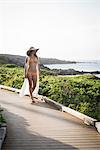 Mid adult woman wearing sunhat and bikini strolling on walkway, Maui, Hawaii, USA
