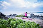 Woman practicing warrior yoga pose on beach, Hawea Point, Maui, Hawaii, USA