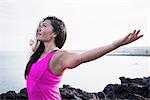 Woman at coast practicing yoga with arms open, Hawea Point, Maui, Hawaii, USA