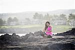 Woman at coast practicing yoga in lotus position, Hawea Point, Maui, Hawaii, USA