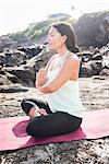Woman practicing yoga lotus position on beach