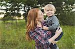 Mother holding young son in field