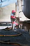 Worker sandblasting boat hull in shipyard