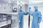 Male worker inspecting machinery in flexible electronics factory clean room