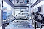 Male worker looking through window of manufacturing machinery in flexible electronics factory clean room