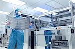 Male worker holding flex circuit in flexible electronics factory clean room