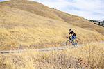 Young male mountain biker on rural road, Mount Diablo, Bay Area, California, USA