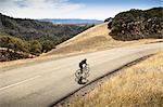 Elevated view of young man mountain biking down rural road, Mount Diablo, Bay Area, California, USA