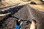 Over the shoulder view man mountain biking on dirt track, Mount Diablo, Bay Area, California, USA