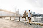 Two male running friends warming up in front of Brooklyn bridge, New York, USA