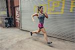 Young female runner running in city street
