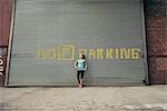 Young female runner leaning against shutter