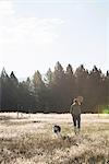 Front view of mid adult woman walking dog looking down smiling, Missoula, Montana, USA