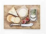 Overhead view of cheese selection with figs on wooden cheese board