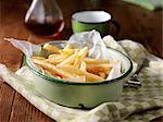 French fries in vintage bowl on tea towel, with vinegar bottle