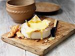 French baking camembert melted with bread sticks on wooden chopping board