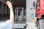 Male factory worker guiding forklift truck at crane factory, China