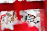 Close up of male factory worker spray painting a red crane in factory workshop, China