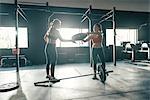 Female crossfitters preparing barbell weights in gym