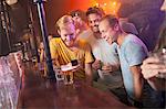 Group of friends smiling at smartphone in club