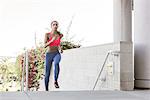 Young woman wearing sports clothing running up stairway looking at camera