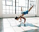 Young man in gym doing handstand, legs raised