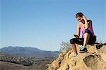 Female runner choosing smartphone music on top of hill, Thousand Oaks, California, USA