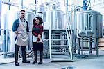 Colleagues in brewery holding clipboard looking at camera smiling