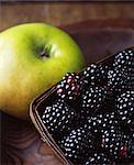 Close up of green apple and blackberries in wooden basket