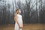 Portrait of long blond haired girl looking away in forest field