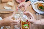 Three women having lunch together at home, making a toast, close-up of glasses