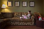 Young girl sitting crossed legged on sofa reading