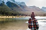 Young boy beside river, rear view, Three Sisters, Rocky Mountains, Canmore, Alberta, Canada