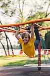 Portrait of boy hanging from park climbing frame