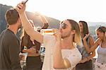 Young man taking selfie drinking beer at waterfront roof terrace party, Budapest, Hungary