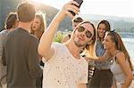 Young man taking selfie at waterfront roof terrace party, Budapest, Hungary