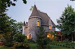 2006 reproduction of a 16th century grey stone and mortar Renaissance castle style residential home facade, at dusk, in summer, Quebec, Canada