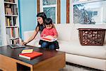 Woman using laptop while toddler son looking at notebook on sofa