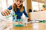 Girl doing science experiment, pouring liquid into flask