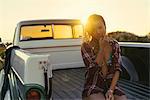 Portrait of young female surfer in back of pickup truck at Newport Beach, California, USA