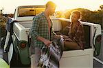 Surfing couple in back of pickup truck at sunset at Newport Beach, California, USA