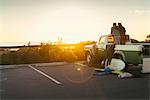 Rear view of couple in back of pickup truck watching sunset at Newport Beach, California, USA