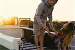 Couple holding hands at back of pickup truck at Newport Beach, California, USA