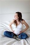 Smiling pregnant woman on bed