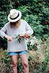 Teenage girl cutting rowan tree branch