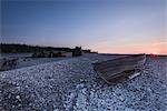 Wooden boat on rocky beach at sunset