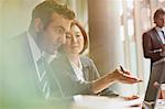 Business people working at laptop in meeting