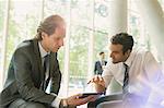 Businessmen meeting using digital tablet in office lobby