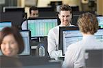 Businessmen working at computers in open plan office